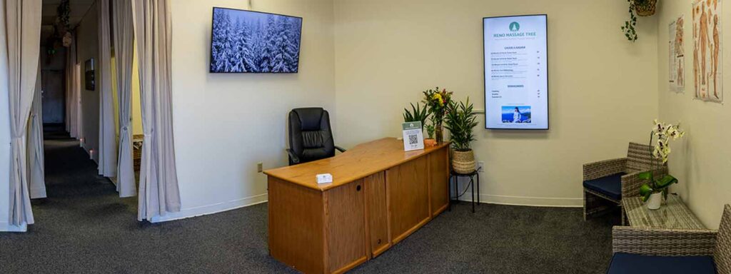 Reception area of Reno Massage Tree with front desk, seating, and massage menu display