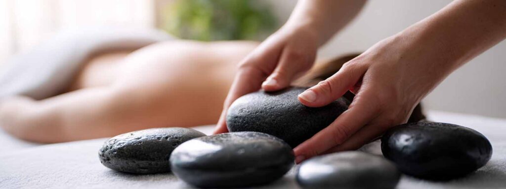 Therapist placing heated stones on a client’s back during a hot stone massage in Reno