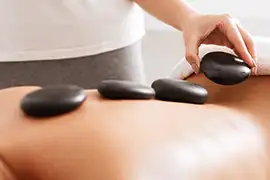 Therapist placing heated stones during a hot stone massage at Reno Massage Tree in Reno, Nevada to relieve tension and promote deep relaxation
