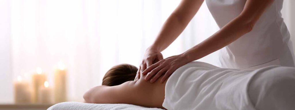 Therapist performing gentle lymphatic drainage massage with candles in a calm spa setting in Reno