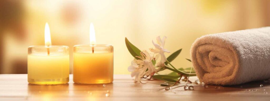 Two lit candles, white towel, and flowers on a spa table symbolizing massage prices in Reno