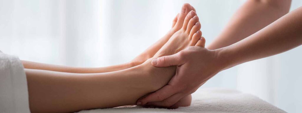 Therapist applying pressure to a client’s feet during a reflexology massage session in Reno